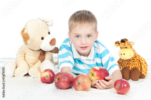 Foto: Little smiling boy eating apple on white Little smiling boy eating apple on white