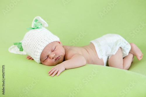 Foto: Funny sleeping newborn baby. Bunny cap on head of girl. Funny sleeping newborn baby. Bunny cap on head of girl.