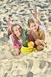 Photo: Two Happy little girl with fruit on the beach Two Happy little girl with fruit on the beach