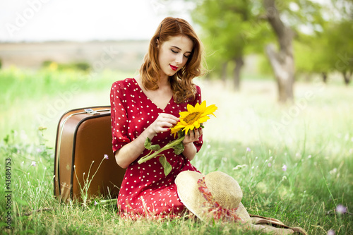 Photo: Redhead girl with sunflower at outdoor. Redhead girl with sunflower at outdoor.