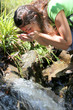 Woman on a trekking day drinking water from river