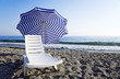 Chaise lounge with umbrella standing on coastline