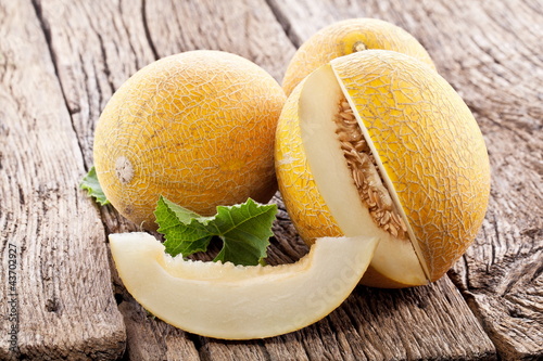 Foto: Melon with slices and leaves on a old wooden table. Melon with slices and leaves on a old wooden table.