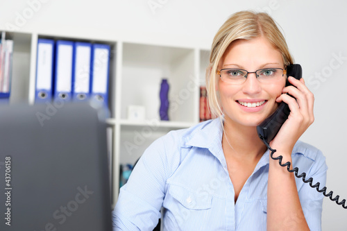 Photo: Junge blonde Mitarbeiterin telefoniert im Büro Junge blonde Mitarbeiterin telefoniert im Büro