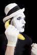 mime in white hat holding a banana in his hand
