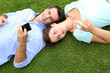Photo: Couple relaxing in grass while using smartphone Couple relaxing in grass while using smartphone