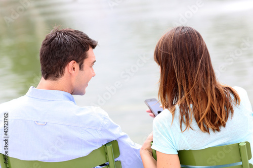 Photo: Back view of couple sitting in chairs in public park Back view of couple sitting in chairs in public park
