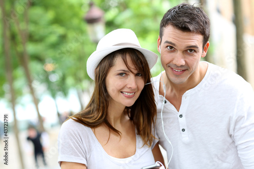 Photo: Couple in town using smartphone and handsfree device Couple in town using smartphone and handsfree device