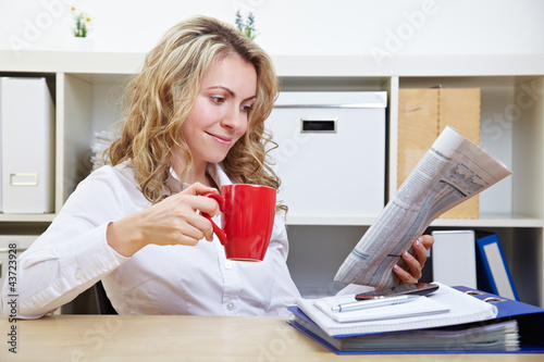 Foto: Frau im Büro liest Zeitung Frau im Büro liest Zeitung