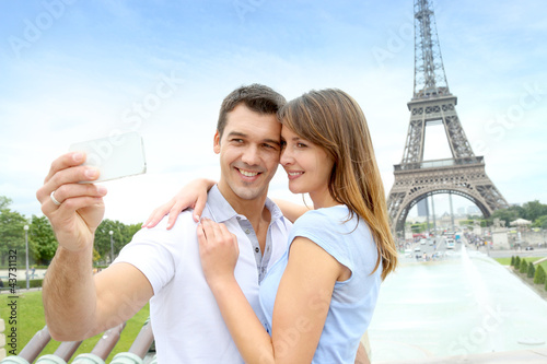 Photo: Couple in Paris taking pictures in front of Eiffel Tower Couple in Paris taking pictures in front of Eiffel Tower