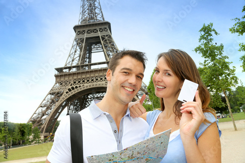 Photo: Couple in front of the Eiffel tower holding tourist pass Couple in front of the Eiffel tower holding tourist pass