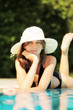 Foto: Junge Frau mit Strohut relaxed am Pool Junge Frau mit Strohut relaxed am Pool