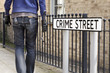 Burglar standing on street with crowbar and leather gloves