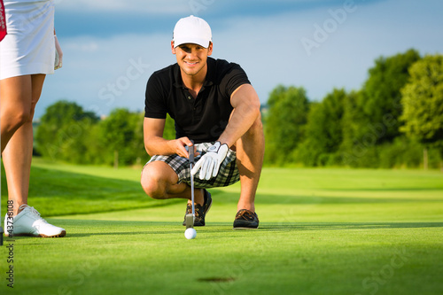 Photo: Junger Golf Spieler am Golfplatz beim Einlochen Junger Golf Spieler am Golfplatz beim Einlochen