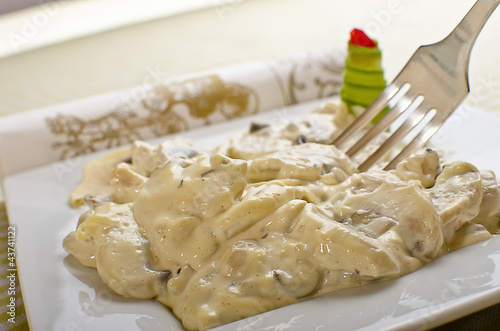 Photo: Mushrooms and white garlic sauce on a white plate. Mushrooms and white garlic sauce on a white plate.