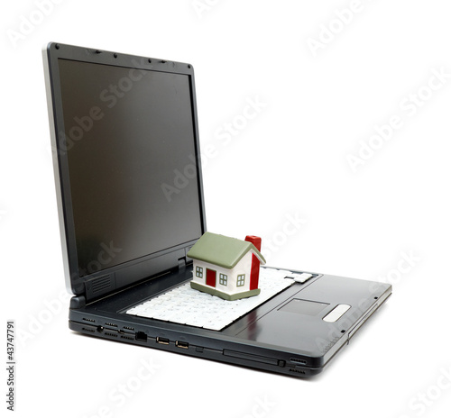 Photo: Toy House on laptop isolated on white backgroun Toy House on laptop isolated on white backgroun