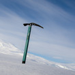 Ice axe with snow-capped mountain in the background