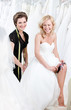 Laughing future bride in wedding gown puts the garter