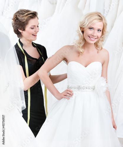 Photo: Seamstress adjusts the dress of the bride Seamstress adjusts the dress of the bride