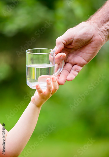 Photo: Little girl taking a glass of water from grandpa Little girl taking a glass of water from grandpa