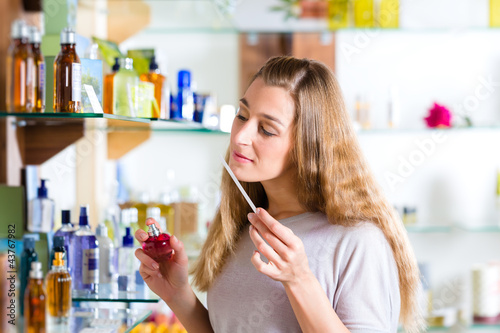 Photo: woman buying perfume in shop or store woman buying perfume in shop or store