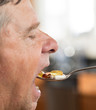 Senior man eating a spoon of vitamins