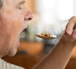 Senior man eating a spoon of vitamins