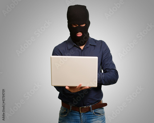 Photo: young male thief holding laptop young male thief holding laptop