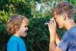Young photographer with a camera shoots her brother outdoors