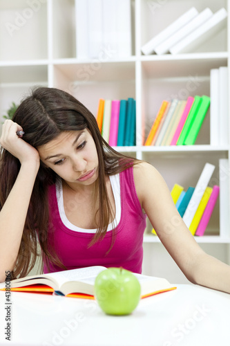 Photo: Teenage girl studying at the desk being tired Teenage girl studying at the desk being tired