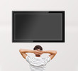 Man watching tv. Photo from behind. Editable copyspace at the sc