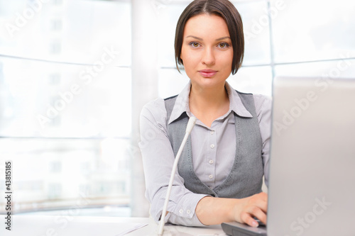 Photo: Business woman working with laptop at her office. Talking online Business woman working with laptop at her office. Talking online