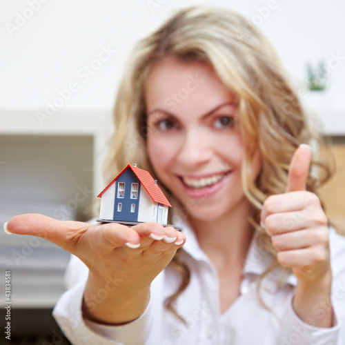 Photo: Frau mit Haus hält Daumen hoch Frau mit Haus hält Daumen hoch