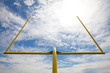 American football goal posts against clouds and blue sky