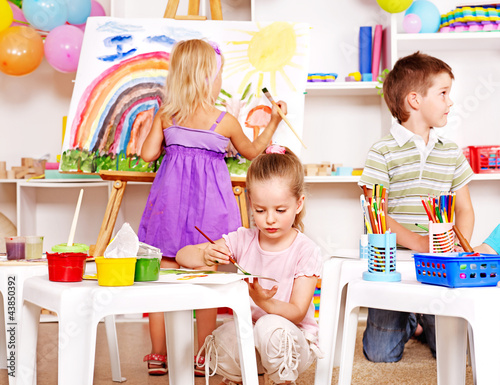 Photo: Child painting at easel. Child painting at easel.
