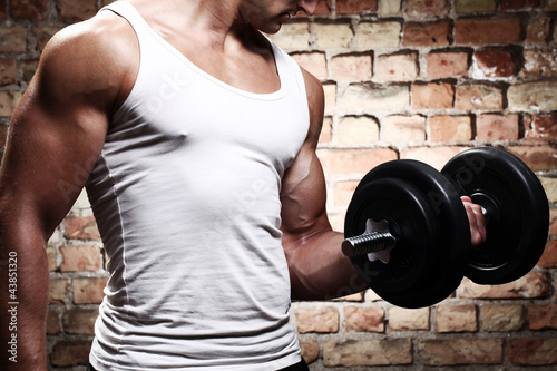 Foto: Muscular guy doing exercises with dumbbell Muscular guy doing exercises with dumbbell
