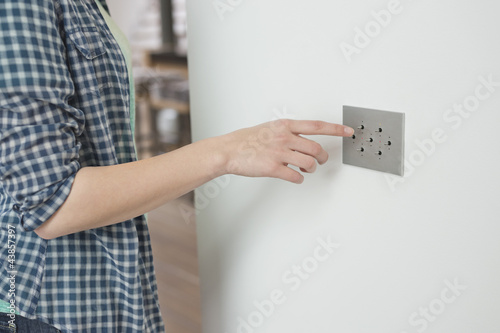 Photo: Woman pressing light switch on a wall Woman pressing light switch on a wall