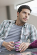 Man reclining on a couch and drinking coffee