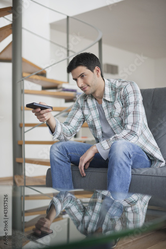 Photo: Man changing channels with a remote control Man changing channels with a remote control