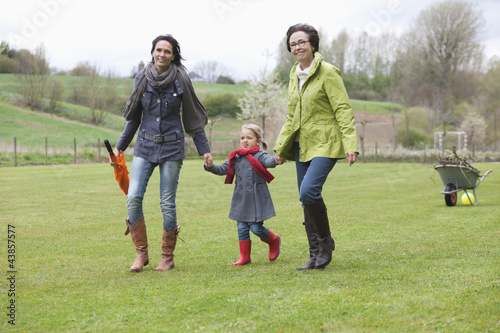 Photo: Girl walking with her mother and grandmother in a lawn Girl walking with her mother and grandmother in a lawn