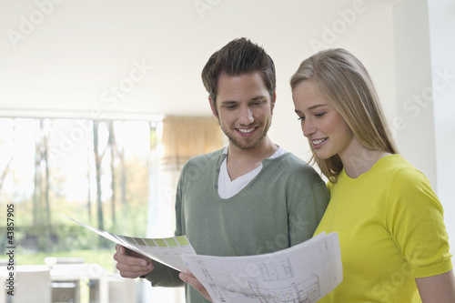 Photo: Couple choosing color for their house from a color chart Couple choosing color for their house from a color chart