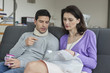 Woman giving medicine to her husband suffering from neckache