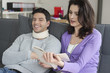 Woman reading a book for her husband suffering from neckache