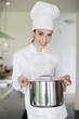 Happy female chef holding a saucepan