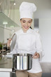 Happy female chef holding a saucepan