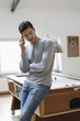 Man leaning against a pool table while talking on a mobile phone