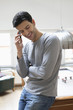 Man leaning against a pool table while talking on a mobile phone