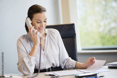 Photo: Businesswoman talking on a landline phone in an office Businesswoman talking on a landline phone in an office