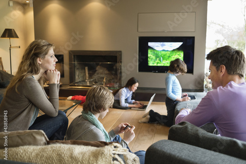 Photo: Family using electronic gadgets in a living room Family using electronic gadgets in a living room