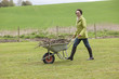 Woman pushing a wheelbarrow full of branches